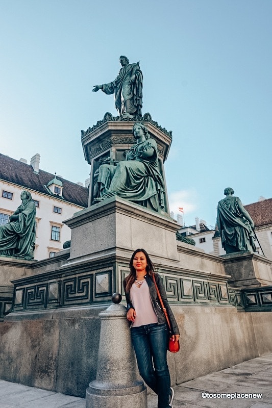 在市中心，女孩在维也纳的雕像前摆姿势