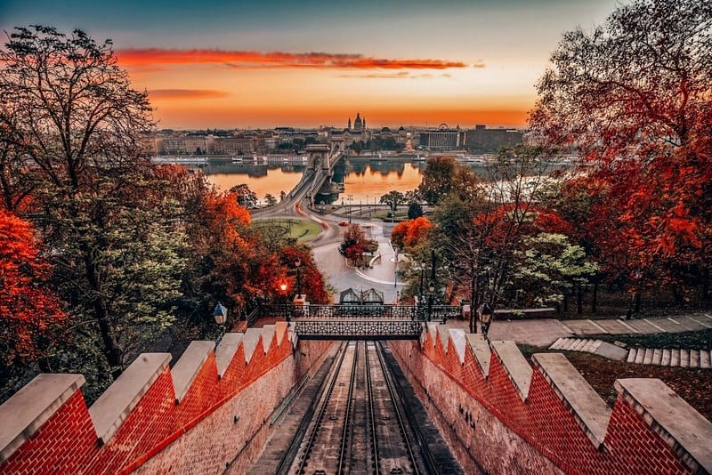 布达佩斯，匈牙利——布达佩斯的秋天。城堡山缆车(Budavári Siklo)与Szechenyi链桥和圣斯蒂芬大教堂日出时的秋叶