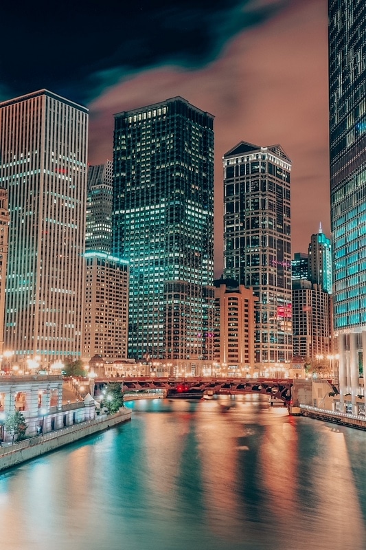 芝加哥河步道，城市摩天大楼在夜晚被灯光和水反射照亮。