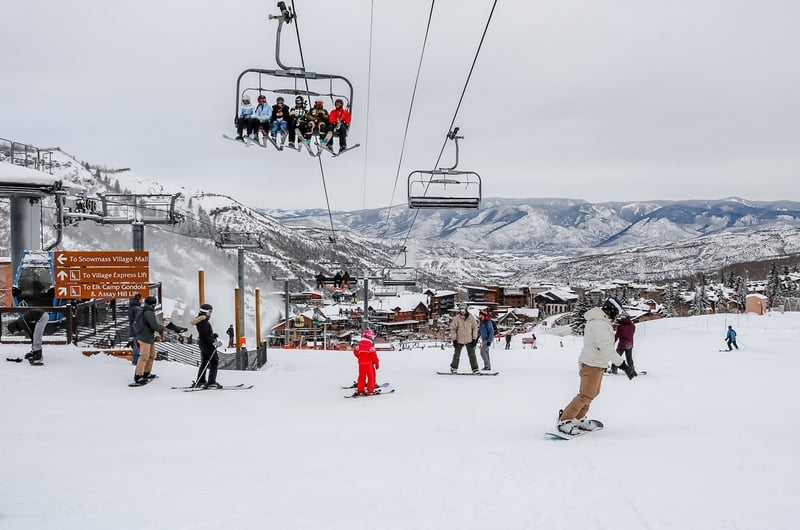 科罗拉多州阿斯彭雪场滑雪场，滑雪者坐在快速缆车上，在雪地上滑雪